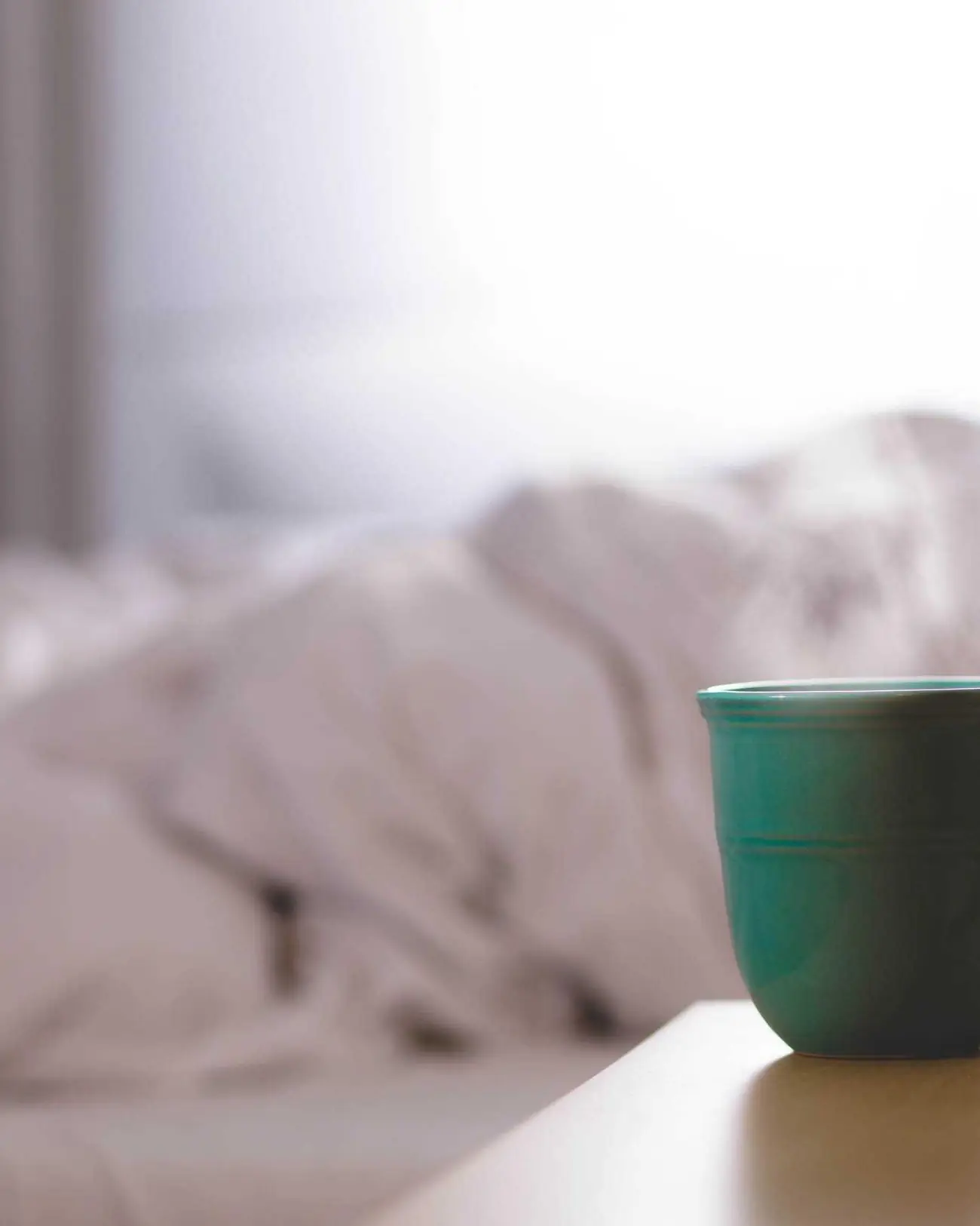 Draps de lin froissés et tasse posée sur la table de nuit